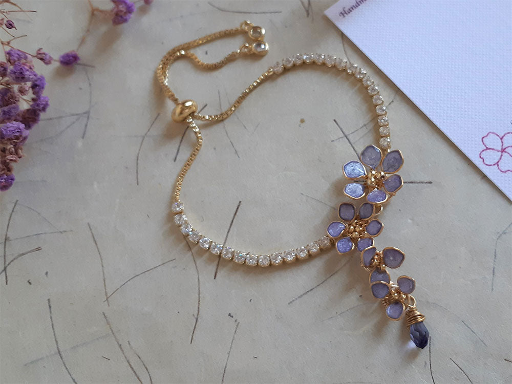 An elegant gold bracelet adjustable with slider.  Wrap around your wrist lavender flowers cascading from crystal chain. 