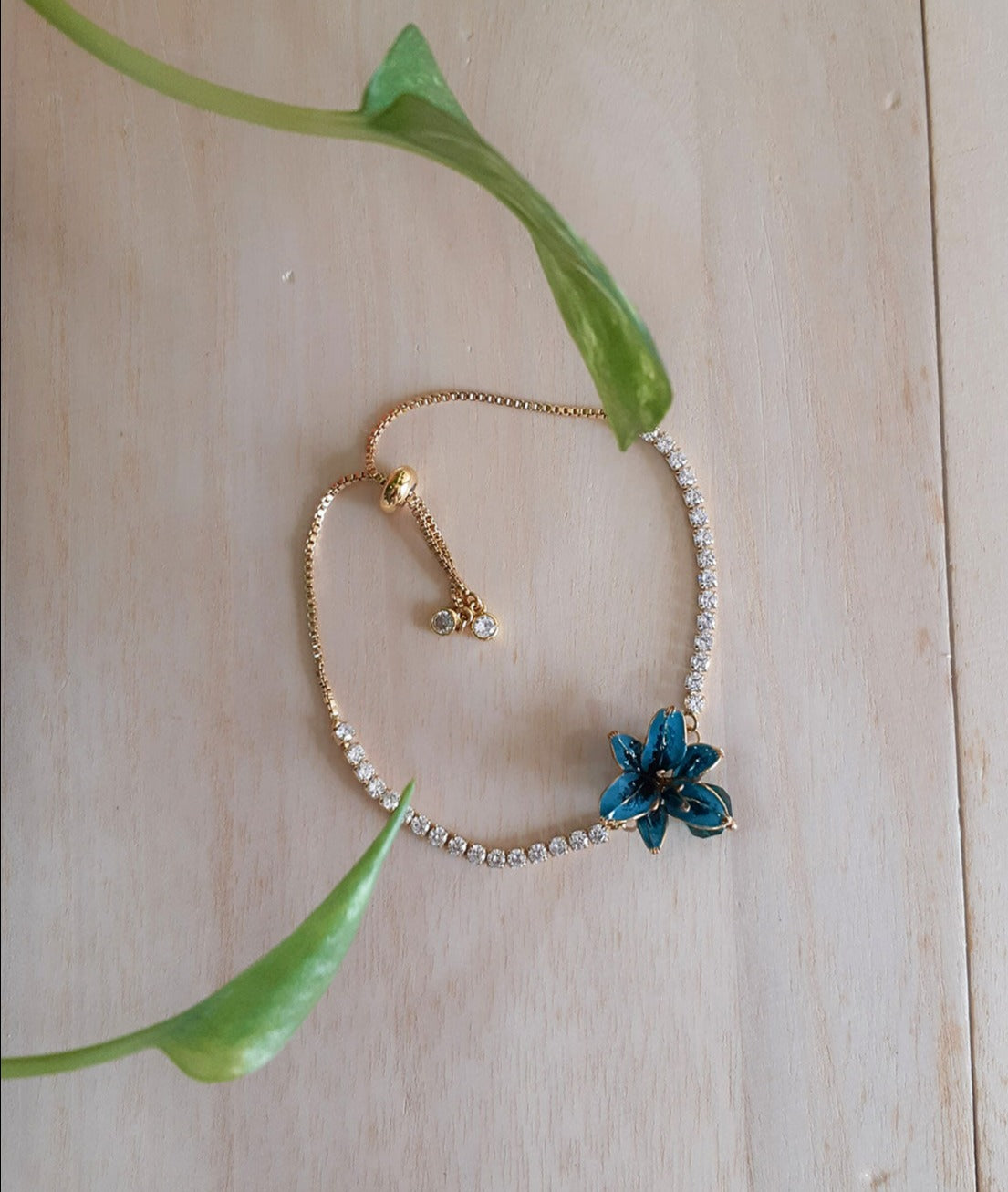 An elegant bracelet with adjustable crystal chain and slider, tiny teal colour Lily flower with a glass bead in the centre, handmade bracelet.