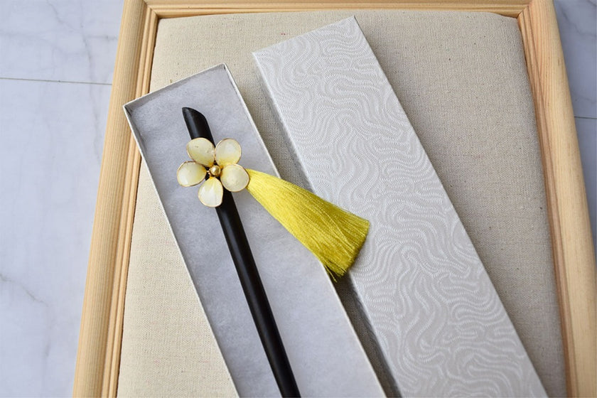 A wooden hair stick, black in colour with Plumeria white flower and yellow dangle silk tassels 