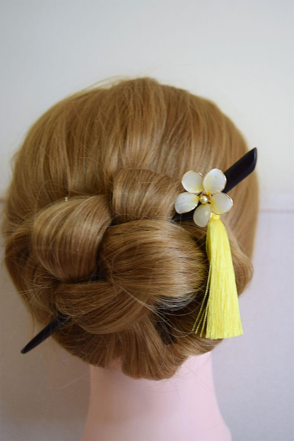 A wooden hair stick, black in colour with Plumeria white flower and yellow dangle silk tassels 